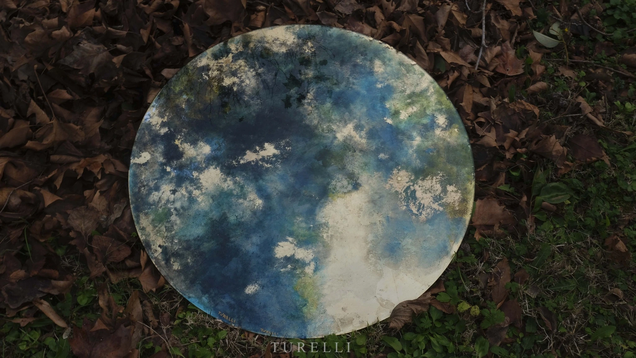 Blue and gold glass moon photographed among leaves